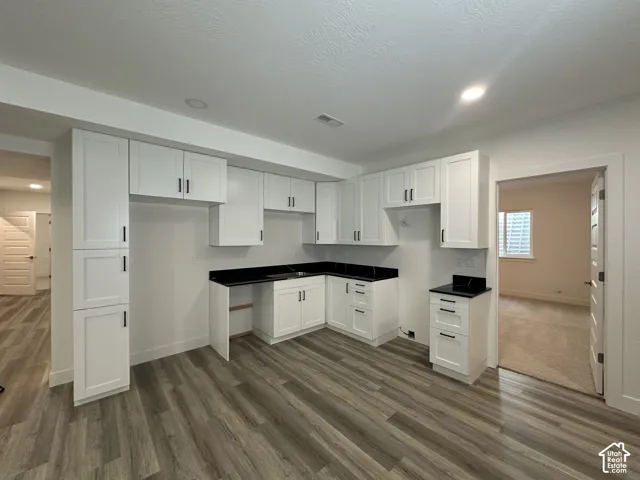 Kitchenette featuring white shaker cabinetry, dark countertops, wood-finish flooring, and recessed lighting