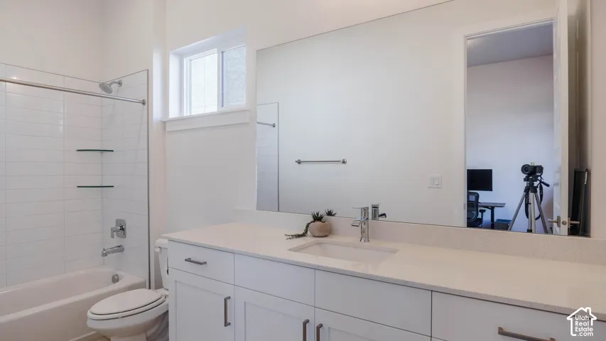 Bathroom featuring a white vanity with an integrated sink, polished chrome faucet, and light-toned countertop