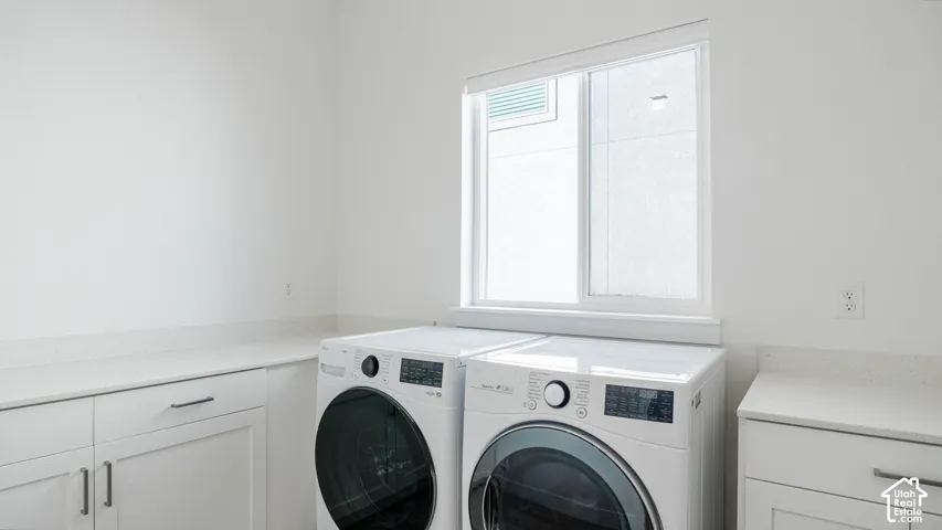 Laundry area featuring white cabinetry, light-toned countertops, and a window