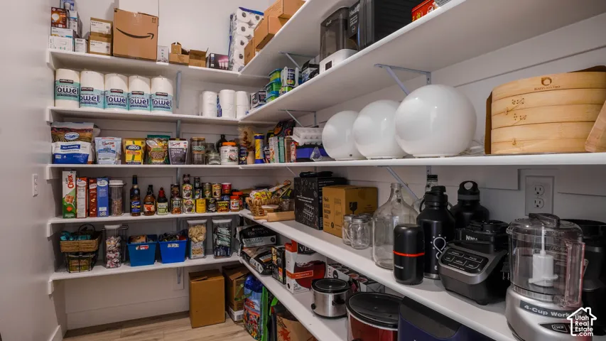 Walk-in pantry featuring extensive white shelving and light wood-finish flooring