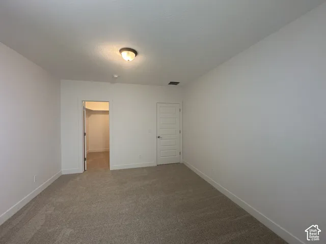 Neutral tone carpet flooring, white walls, white trim, recessed closet, and a white paneled door