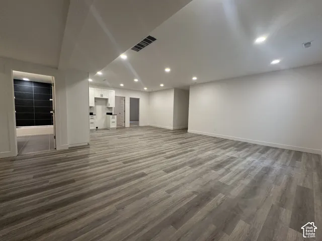 Spacious open-concept room featuring wood-finish flooring, recessed lighting, and a white baseboard trim