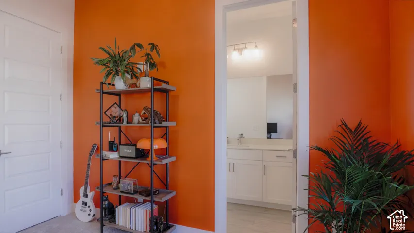 Vibrant interior space featuring a bright orange accent wall, five-panel interior door with brushed nickel hardware, and an open doorway revealing a bathroom with a white vanity and track lighting