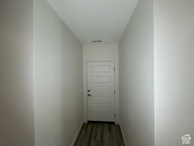 Hallway featuring white painted walls and wood-finish flooring