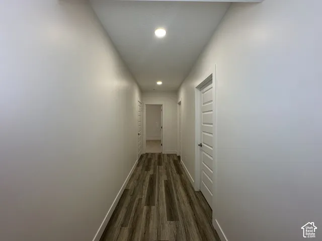 Hallway featuring wood-finish flooring, white walls, recessed lighting, and multiple paneled doors
