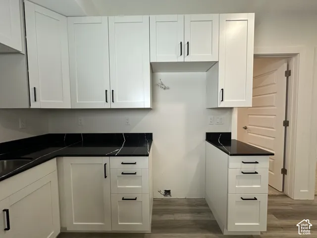 Kitchen featuring white shaker-style cabinetry, black countertops with white veining, and matte black hardware