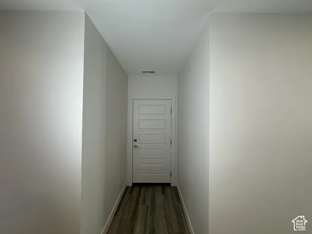 Hallway featuring wood-finish flooring, light neutral wall paint, and a five-panel interior door