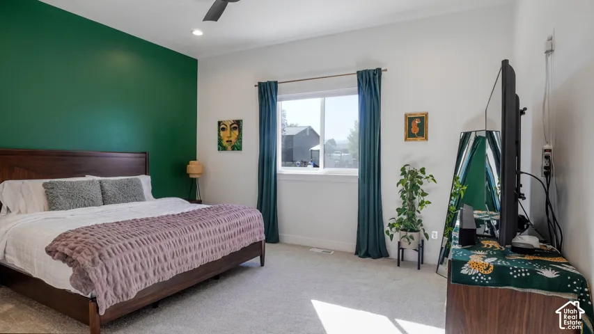 Carpeted room featuring a window with teal drapes, a dark wood-finish bed frame, and a contrasting green accent wall