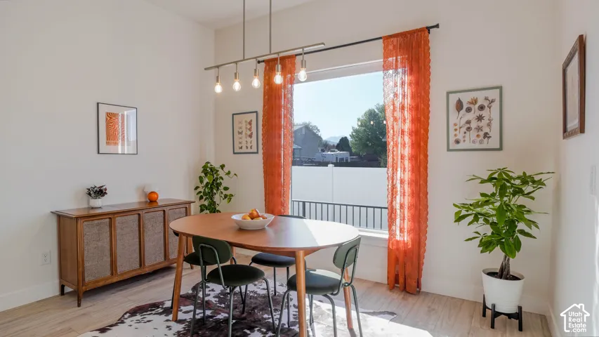 Bright dining area featuring a large window, a linear pendant light fixture, and light wood-finish flooring