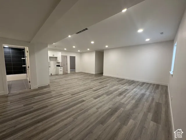 Spacious open-concept room featuring wood-finish flooring, recessed lighting, and a white baseboard trim