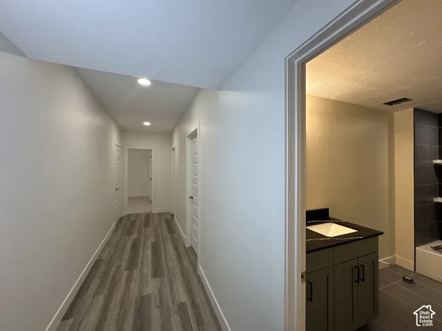 Hallway with wood-finish flooring, recessed lighting, and white paneled doors