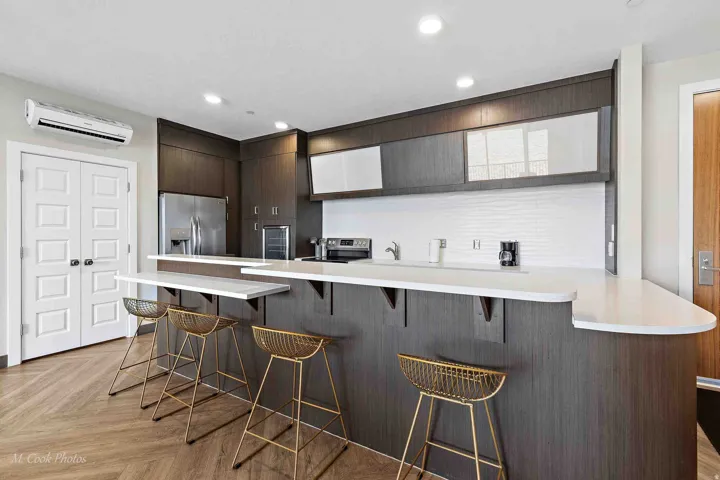 Modern kitchen featuring a sleek dark wood-finish cabinetry with white quartz countertops and a waterfall-edge island