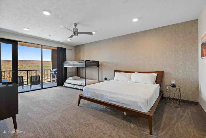 Spacious guest bedroom featuring a wood-frame queen bed, bunk bed configuration, ceiling fan, and recessed lighting