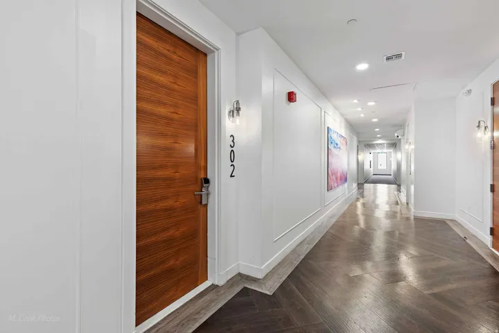Hallway featuring wood-finish flooring in a herringbone pattern, recessed ceiling lighting, and contemporary sconce lighting