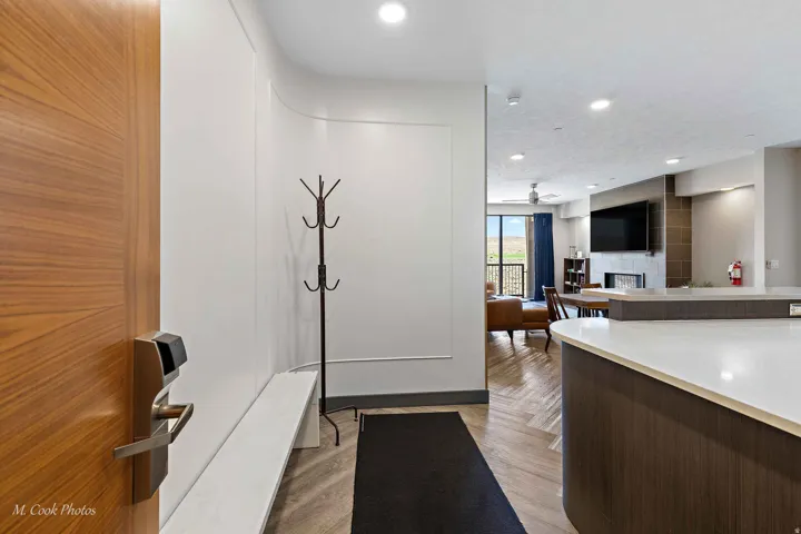 Modern entryway featuring a wood-finish interior door, white shaker-style cabinetry with integrated hardware, recessed ceiling lighting, wood-finish flooring, and a black runner mat