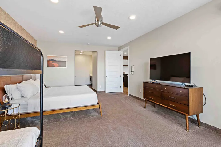 Carpeted room featuring recessed lighting, a modern ceiling fan, and a white paneled door