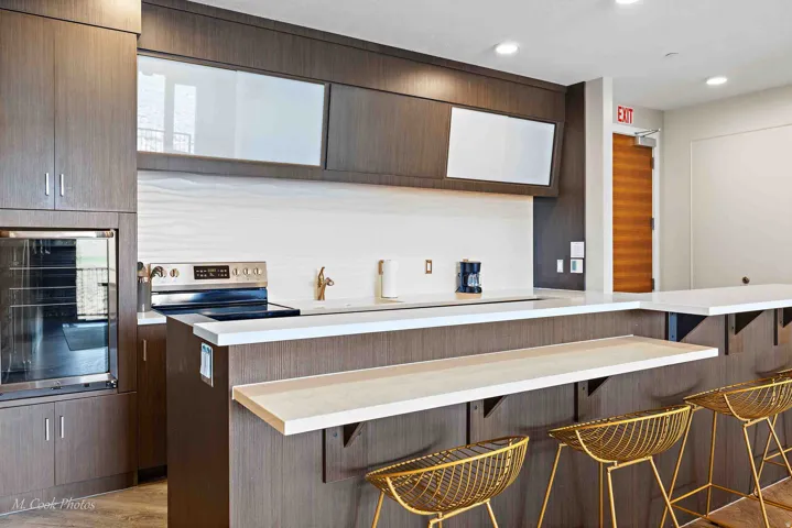 Contemporary kitchen featuring wood-grain cabinetry, a stainless steel range, and a white textured tile backsplash