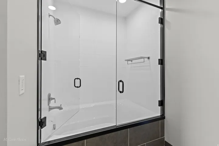 Shower-over-tub combination with clear glass enclosure and matte black hardware