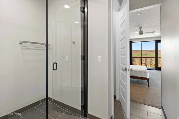 Modern bathroom entry featuring a frameless glass shower enclosure with matte black trim, dark gray tile flooring, and a stainless steel towel bar