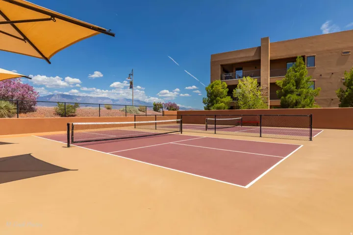 Two outdoor sports courts with red playing surfaces and white line markings