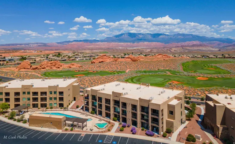 Multi-story residential buildings featuring balconies, a swimming pool, and a shaded lounge area