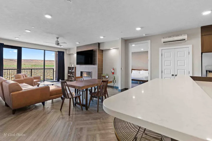 Open-concept living space featuring a white quartz waterfall-edge kitchen island, wood-finish flooring throughout, and recessed ceiling lighting