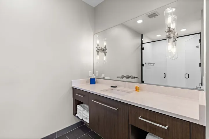 Bathroom featuring a single vanity with a white countertop, an undermount sink, and a wall-mounted faucet