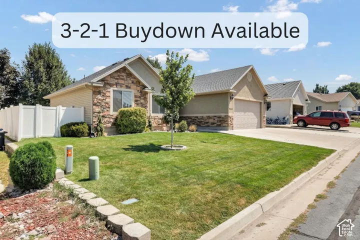 Crafted stone facade, stucco exterior, attached garage, well-maintained lawn, and a white privacy fence