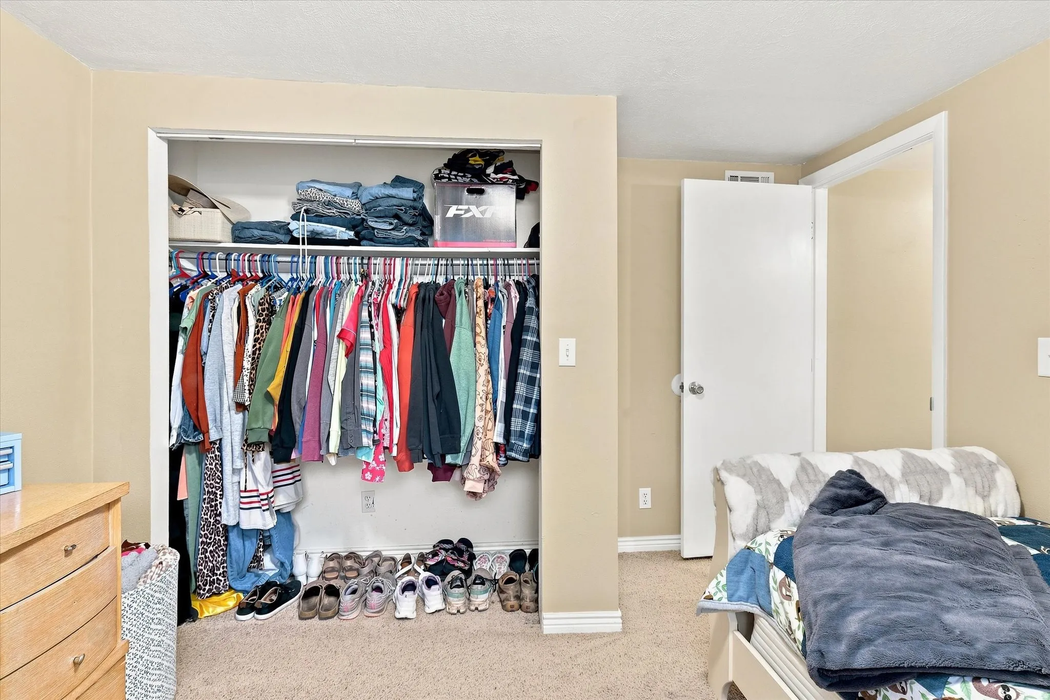Spacious bedroom featuring wall-to-wall closet with dual rods, built-in shelving, and ample storage for clothing and accessories