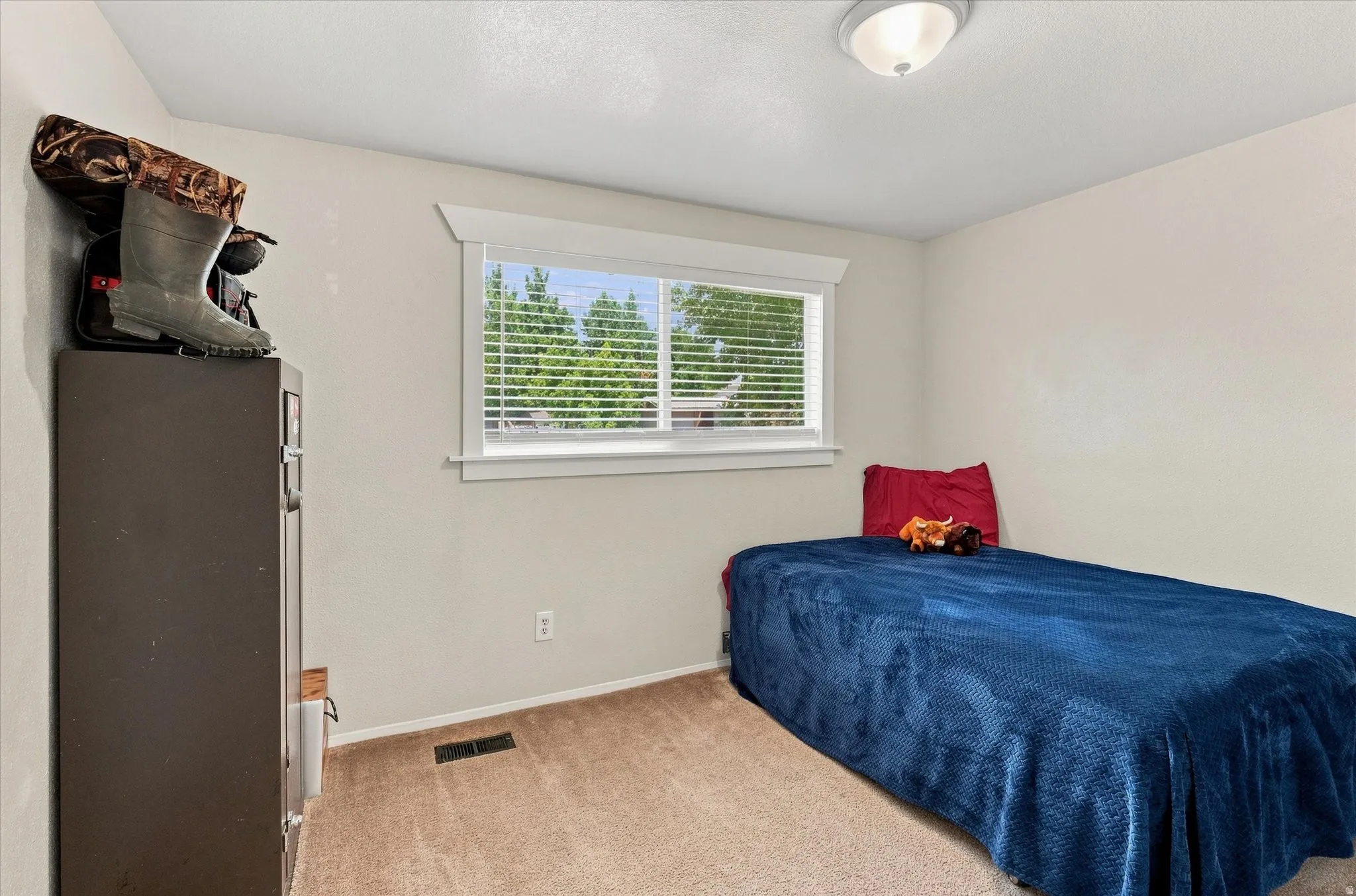 Carpeted room with a single window featuring blinds and white trim