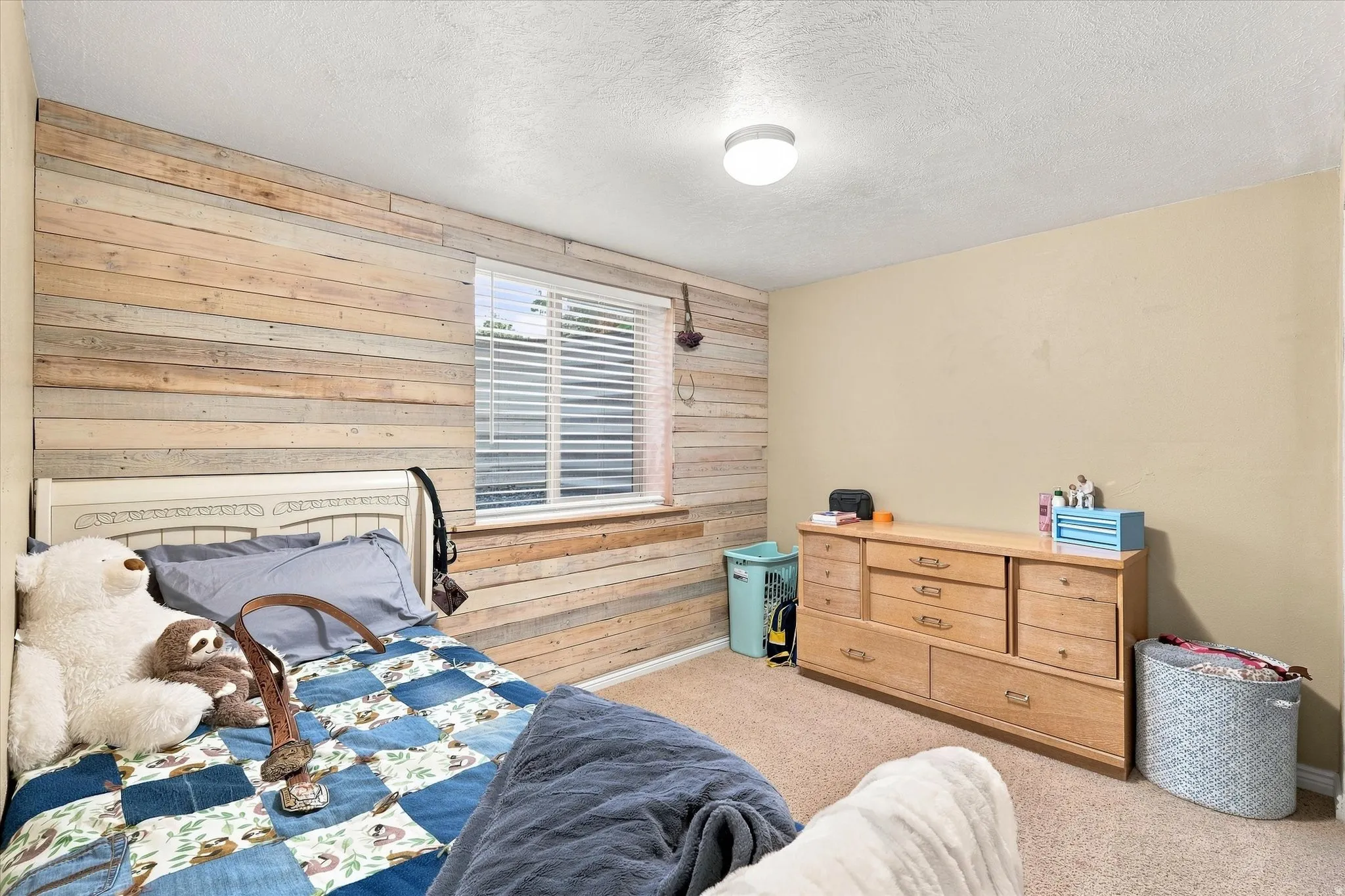 Carpeted interior room featuring a wood-panel accent wall and a window with horizontal blinds