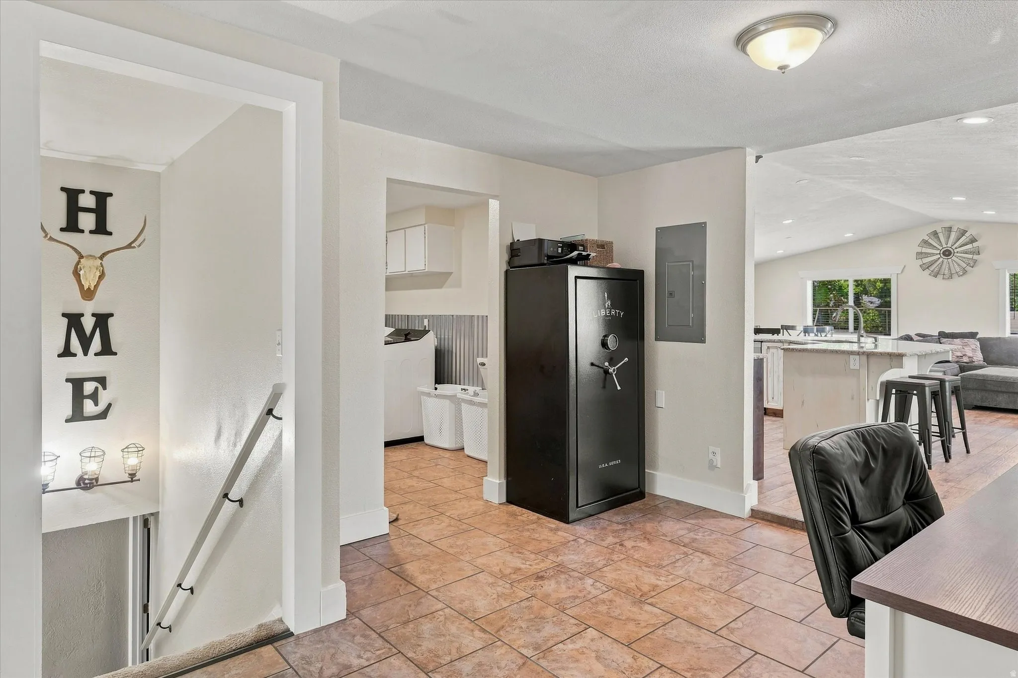 Tiled entry flooring with recessed lighting leading to a laundry area and open-concept living space
