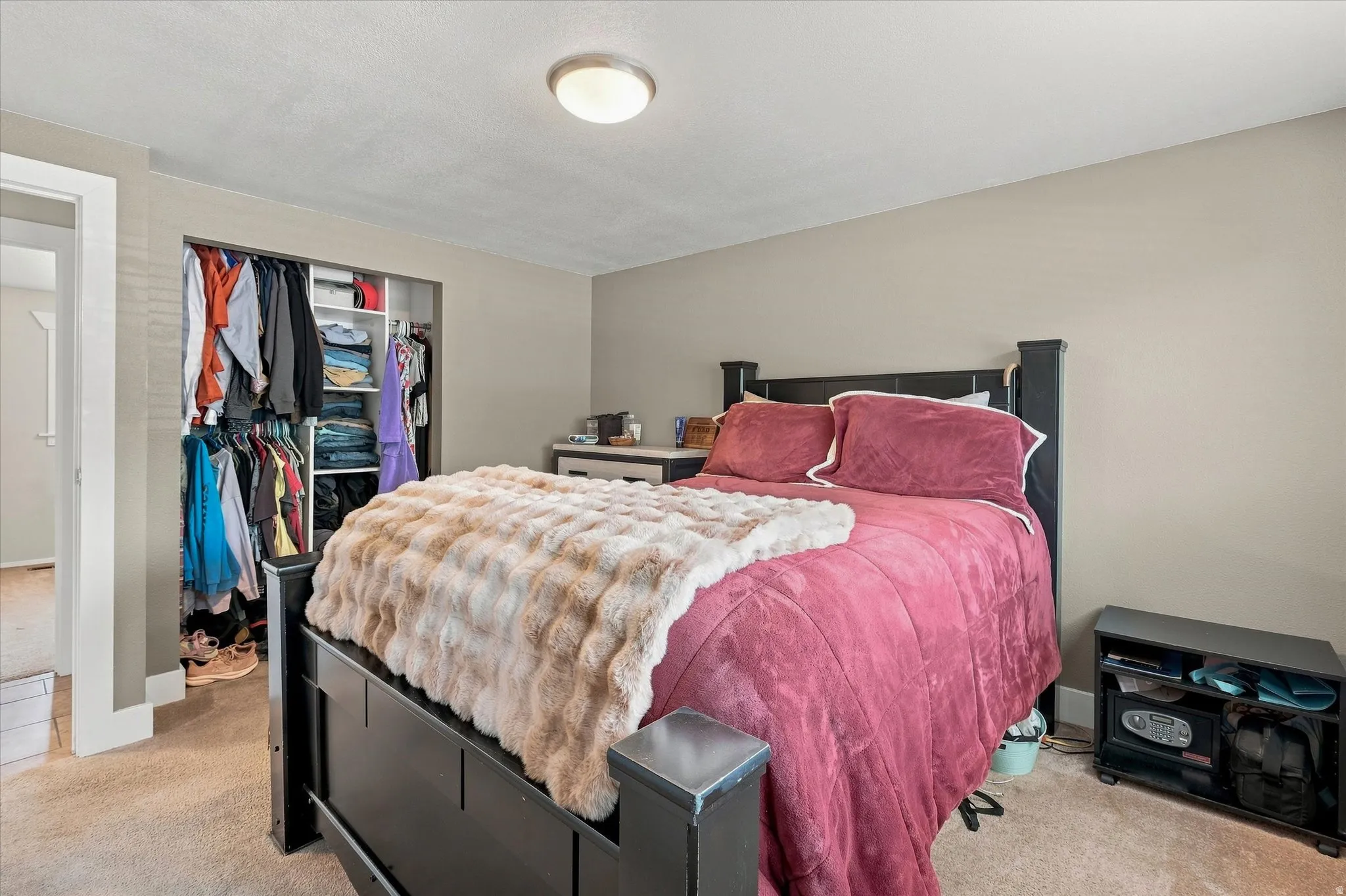 Carpeted bedroom featuring a built-in closet with shelving and hanging rods
