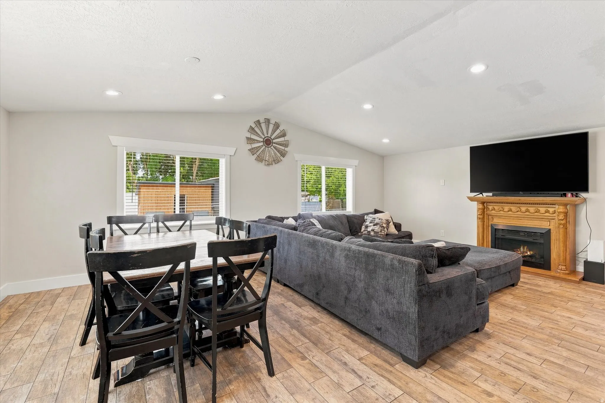 Open-concept living space featuring wood-finish flooring, recessed lighting, and vaulted ceilings