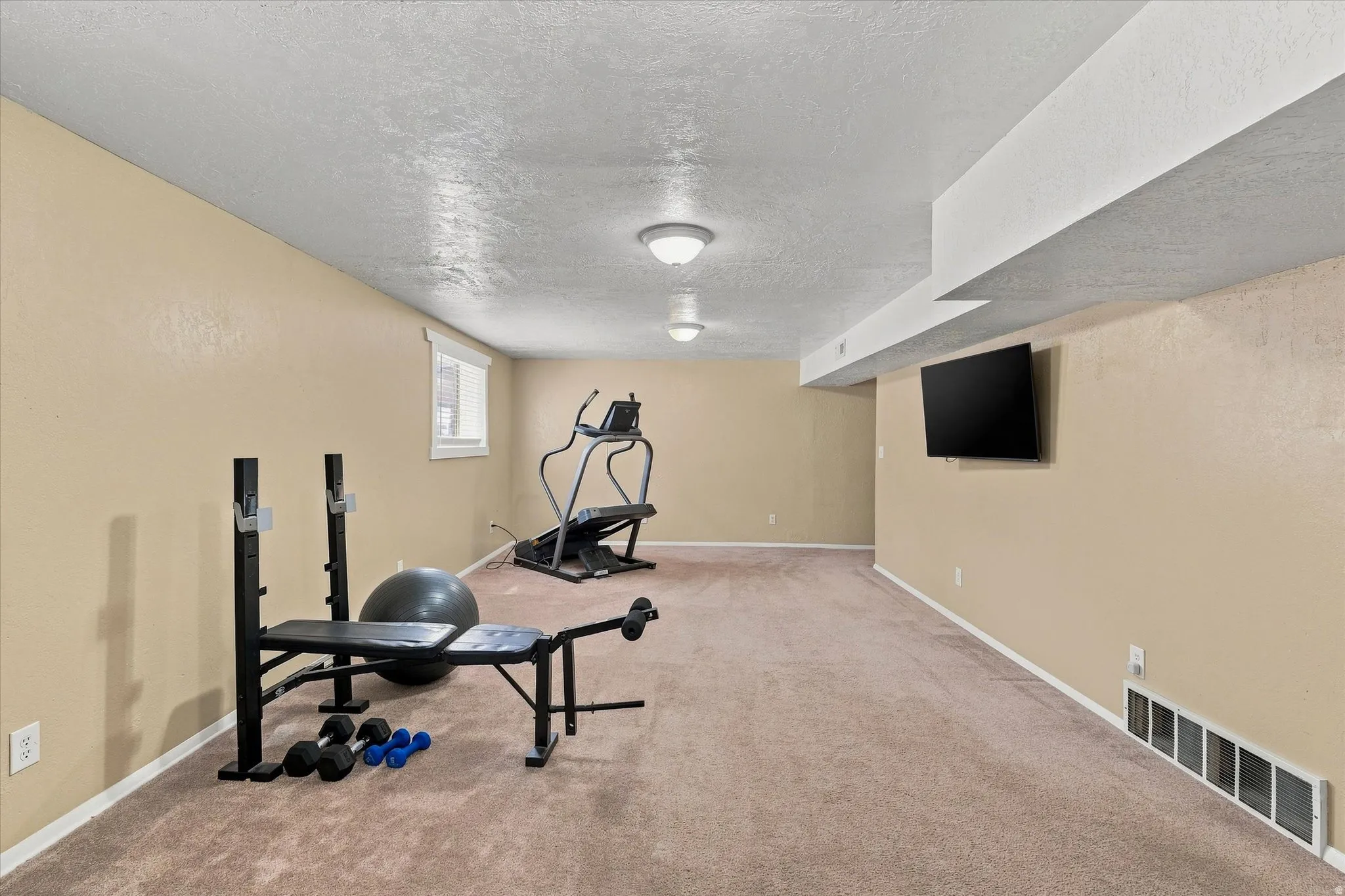 Spacious lower-level room featuring neutral-toned walls, carpeted flooring, and recessed lighting