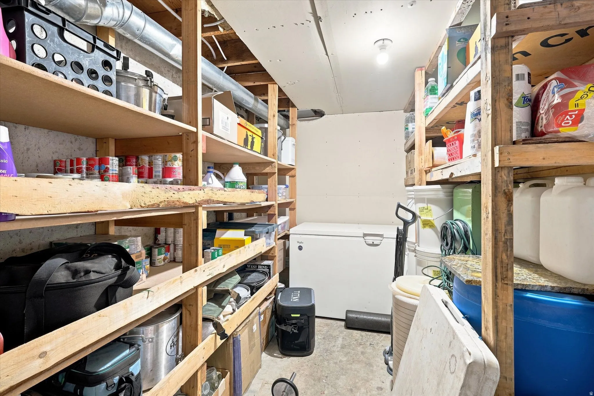 Utility room featuring extensive wooden shelving with multiple storage levels, washer and dryer hookups, and ample space for household supplies and equipment organization