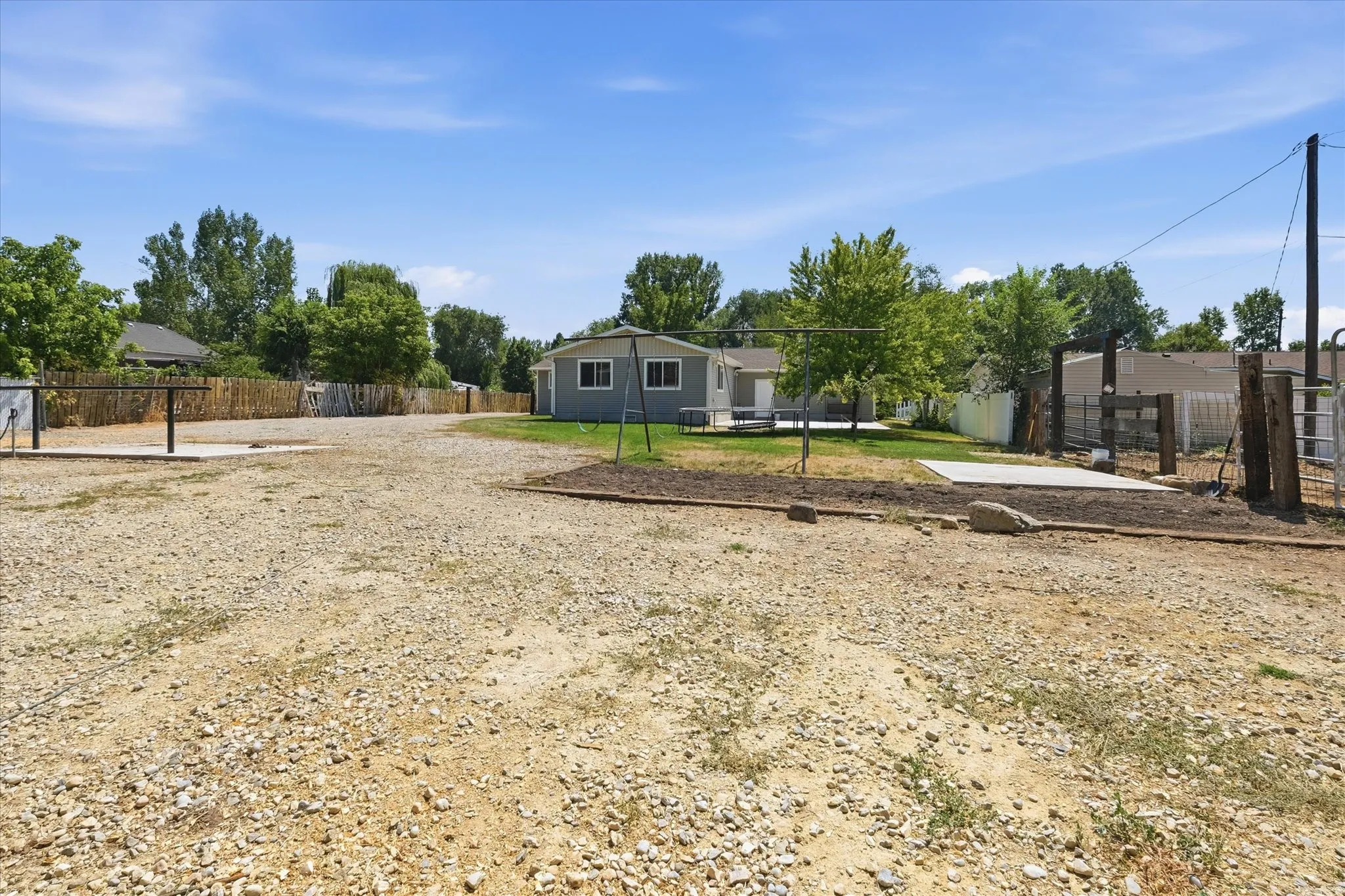 Expansive gravel lot with multiple concrete pads, offering substantial outdoor utility