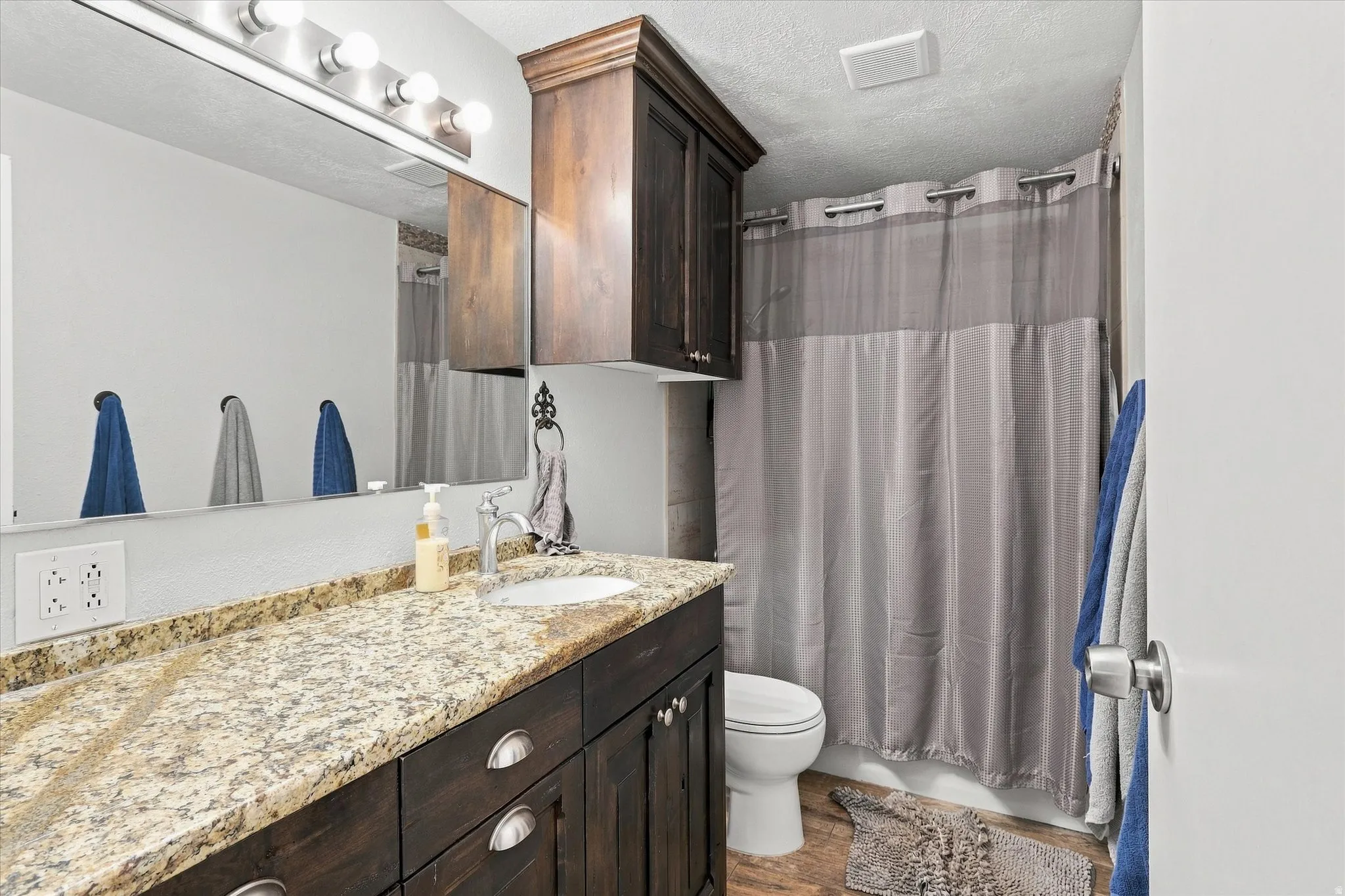 Bathroom vanity featuring a speckled countertop, undermount sink, and dark wood-finish cabinetry