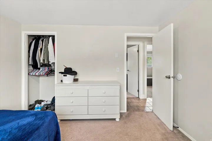 Carpeted interior space with a built-in closet and a white six-drawer dresser