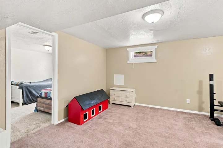 Versatile basement recreation room featuring plush carpeting, generous ceiling height with recessed lighting, and ample square footage for customization
