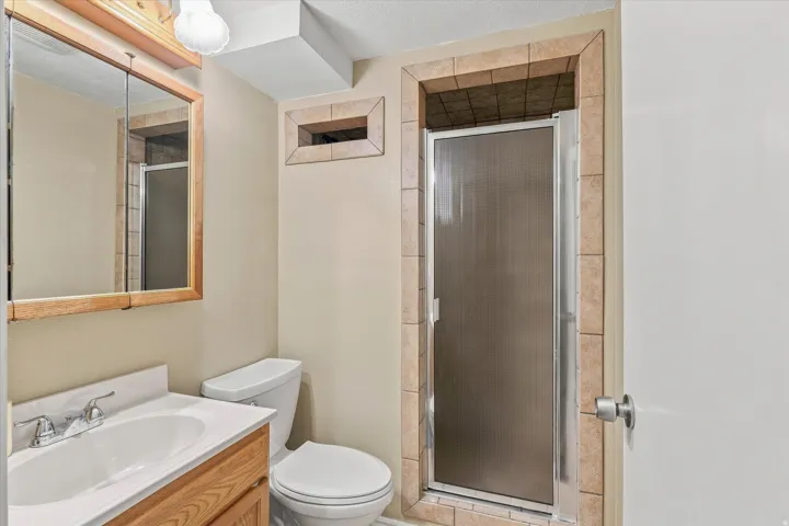 Well-appointed bathroom featuring a wood-finish vanity with dual sink, ceramic tile surround, and large framed mirror