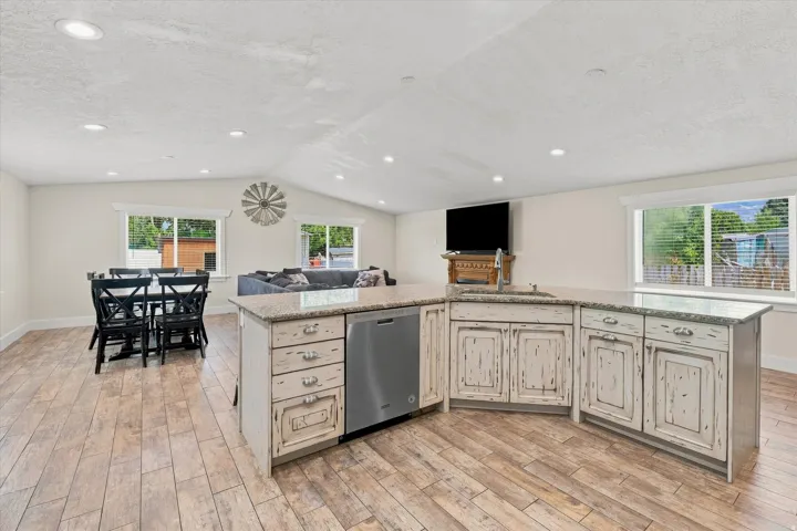 Open-concept living space featuring wood-finish flooring, recessed lighting, and vaulted ceilings