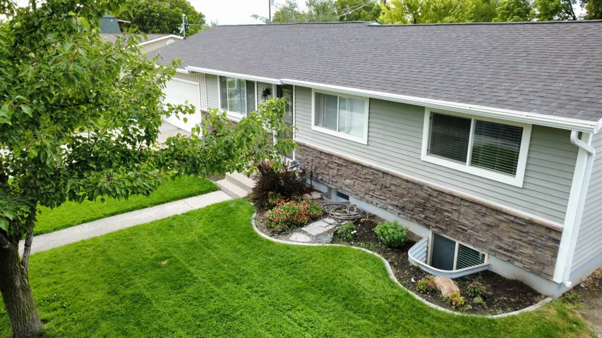 Gray siding exterior with stone-finish accents, asphalt shingle roof, and white-framed windows