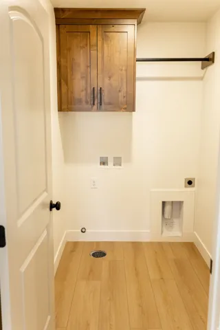 Wood-finish flooring, overhead cabinetry with dark hardware, and a wall-mounted hanging rod