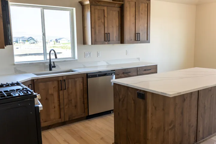 Kitchen featuring wood-finish cabinetry, white countertops, stainless steel appliances, and wood-finish flooring