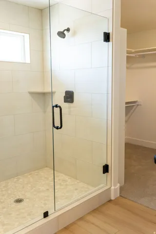 Glass-enclosed shower with a dark bronze shower head and control