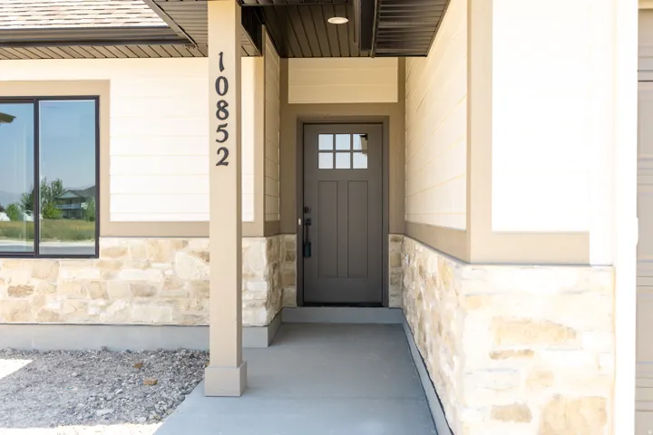 Welcoming entryway featuring a paneled door with glass inserts, stone veneer detailing, and horizontal siding