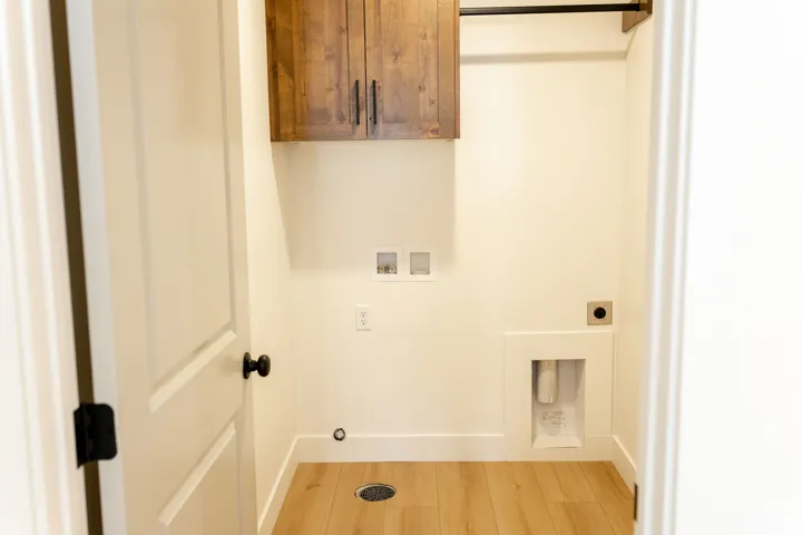 Wood-finish flooring, overhead wood cabinetry, and a built-in hanging rod