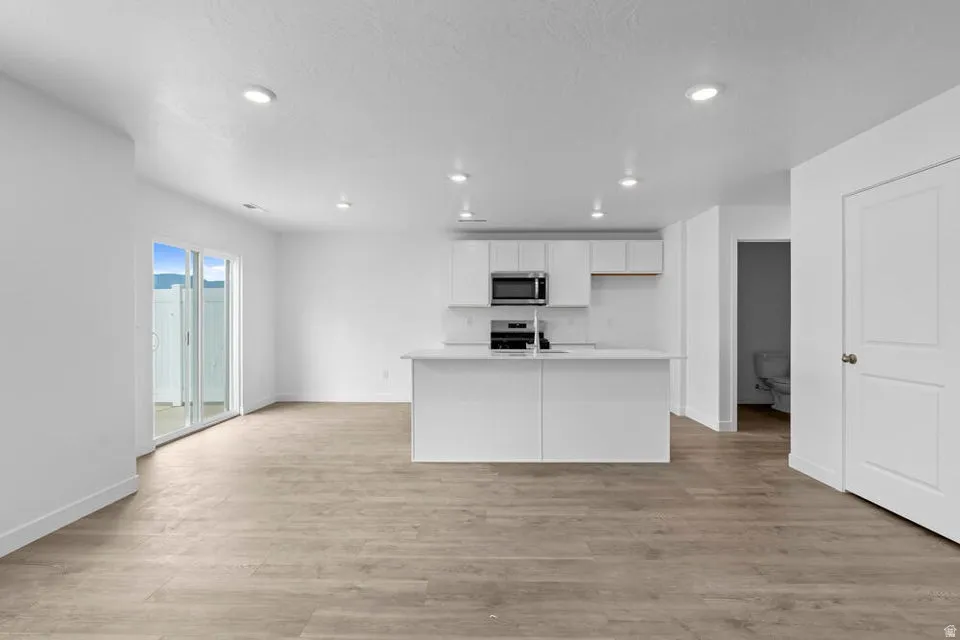 Open-concept living area featuring wood-finish flooring, recessed lighting, and a sliding glass door providing outdoor access