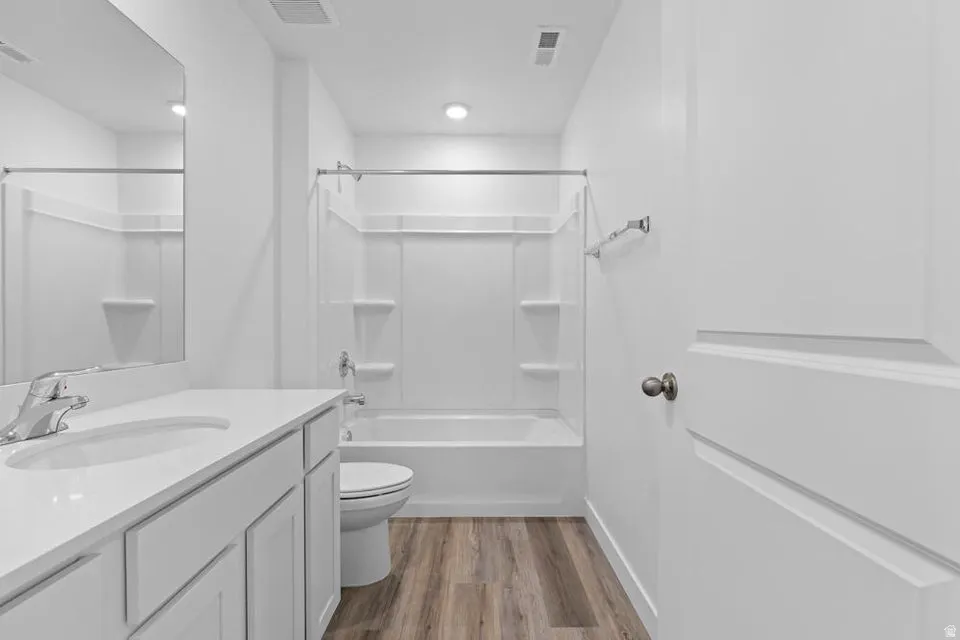 Full bathroom with a white vanity featuring an integrated sink, chrome faucet, and mirrored wall